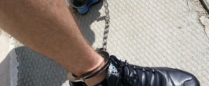 The Sneaker Boy in handcuffs and leg cuffs