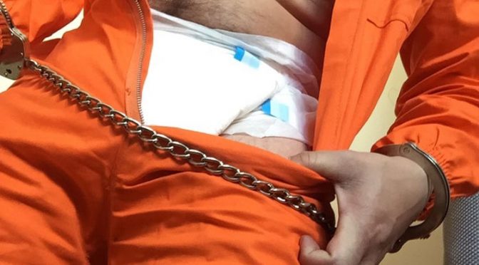 Writing lines in an orange inmate jumpsuit, diaper and shackles