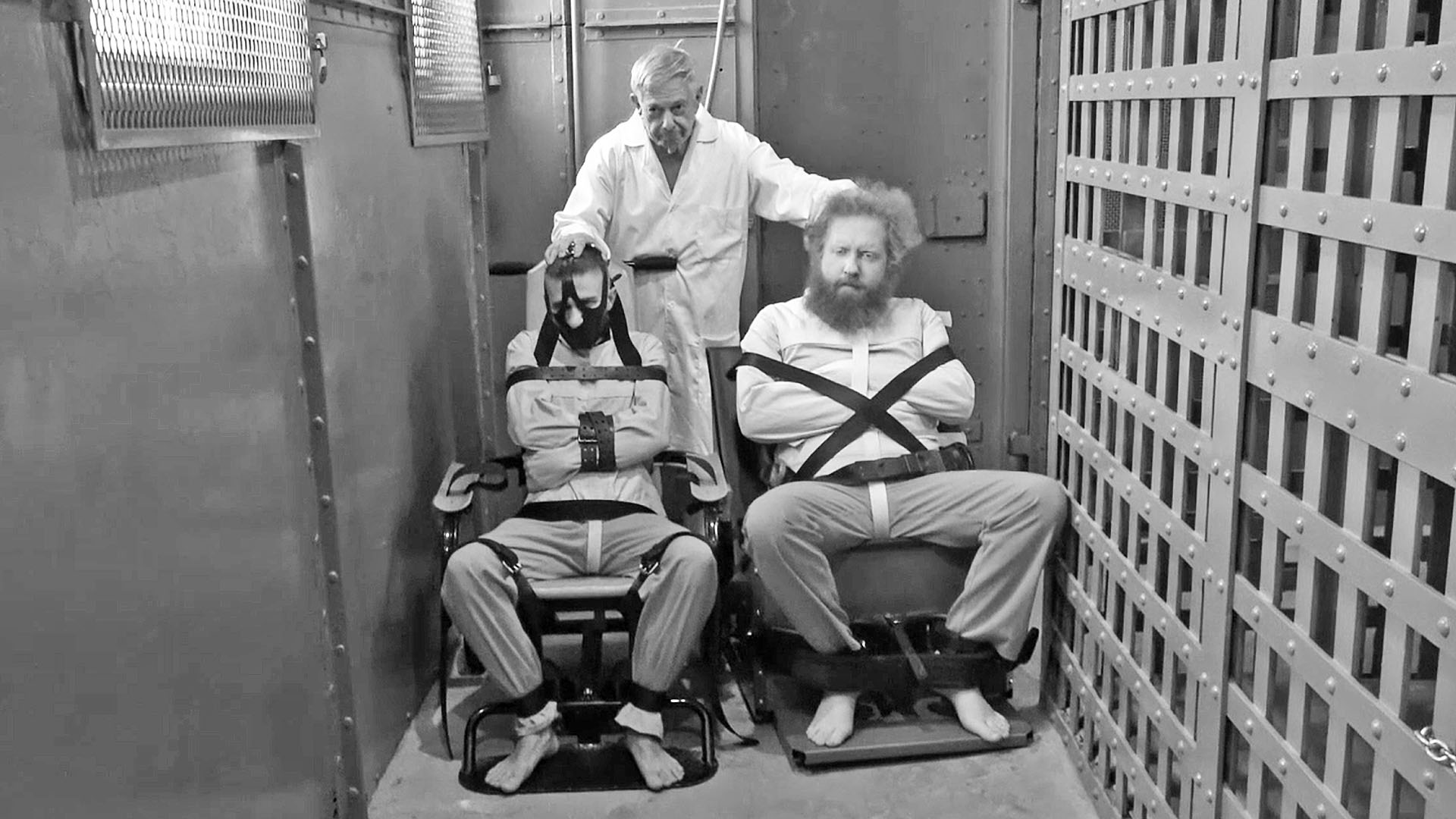 men bound in police restraint chairs and straitjackets
