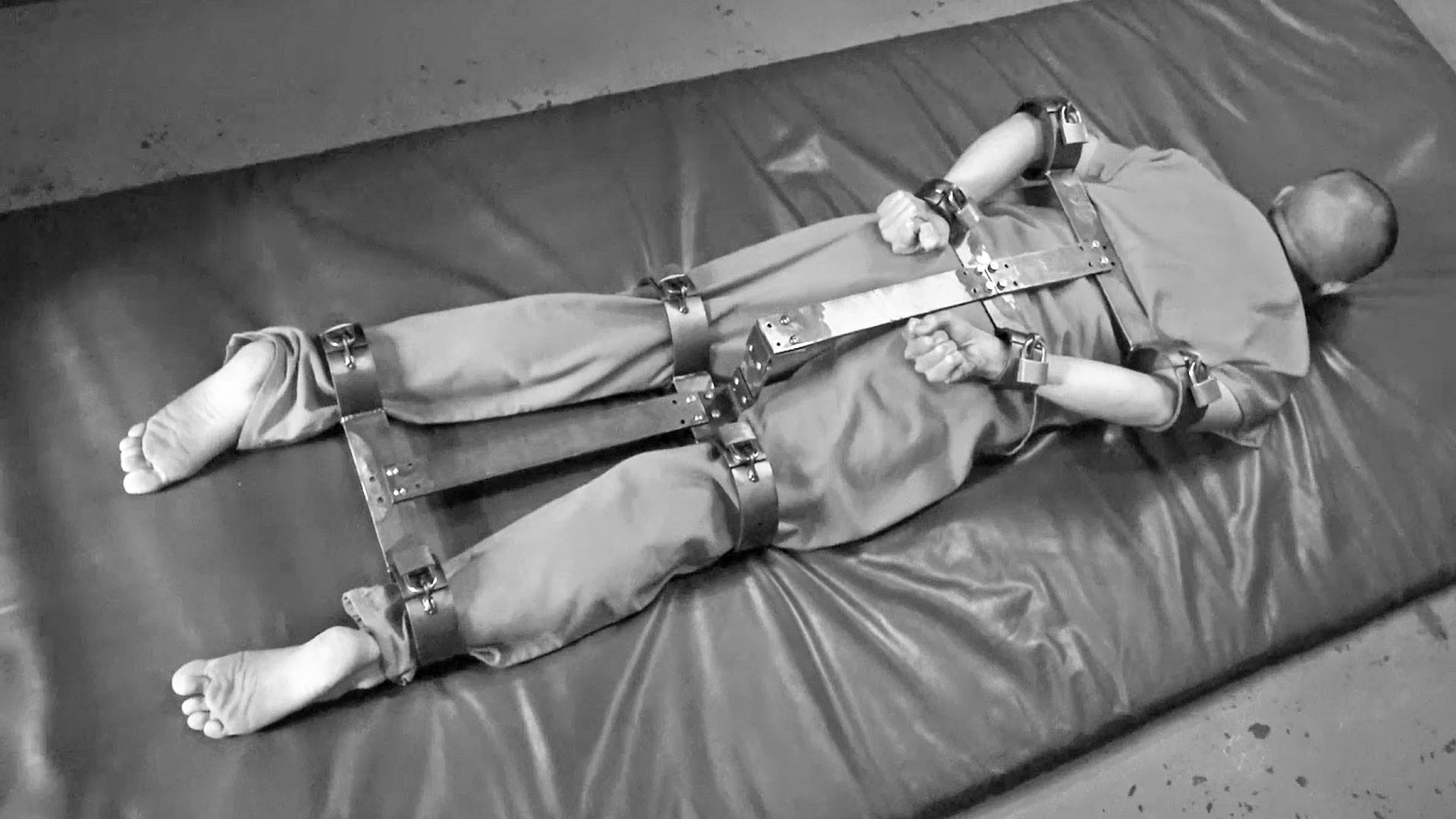 man in rigid metal restraints behind his back