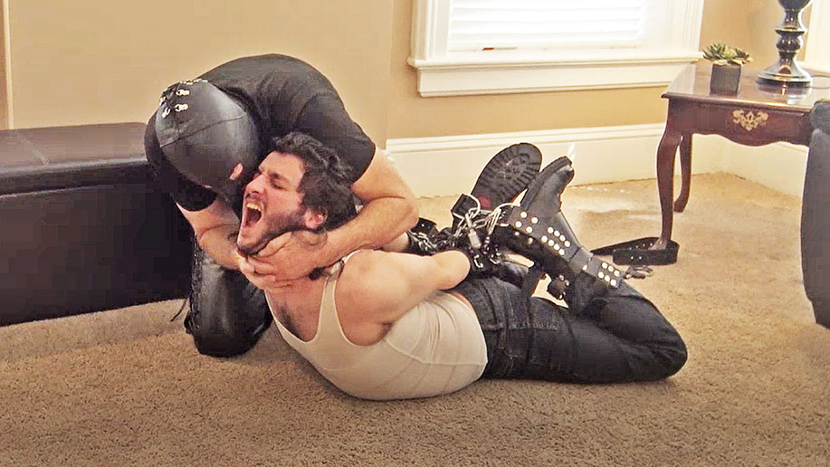 a man in a wife beater is hogtied by a leather sadist