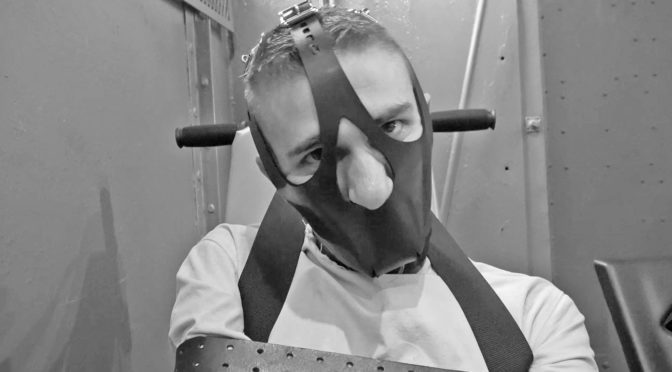 man bound with a face mask in an insane asylum