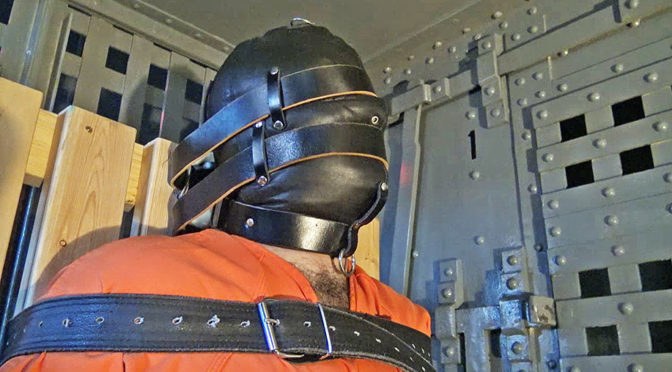 Hooded and strapped inescapably in a bondage chair