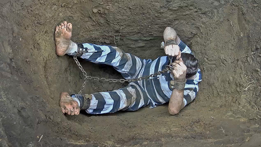 man gets chained up in the dirt