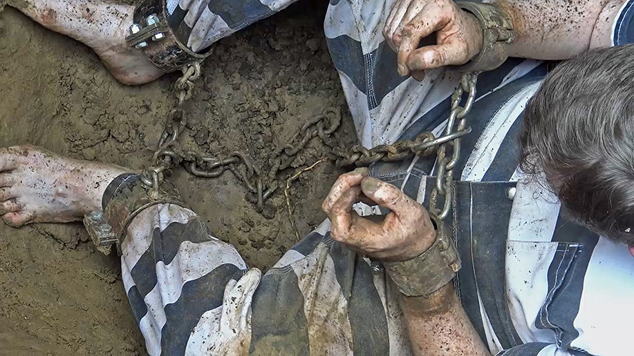 man gets chained up in the dirt